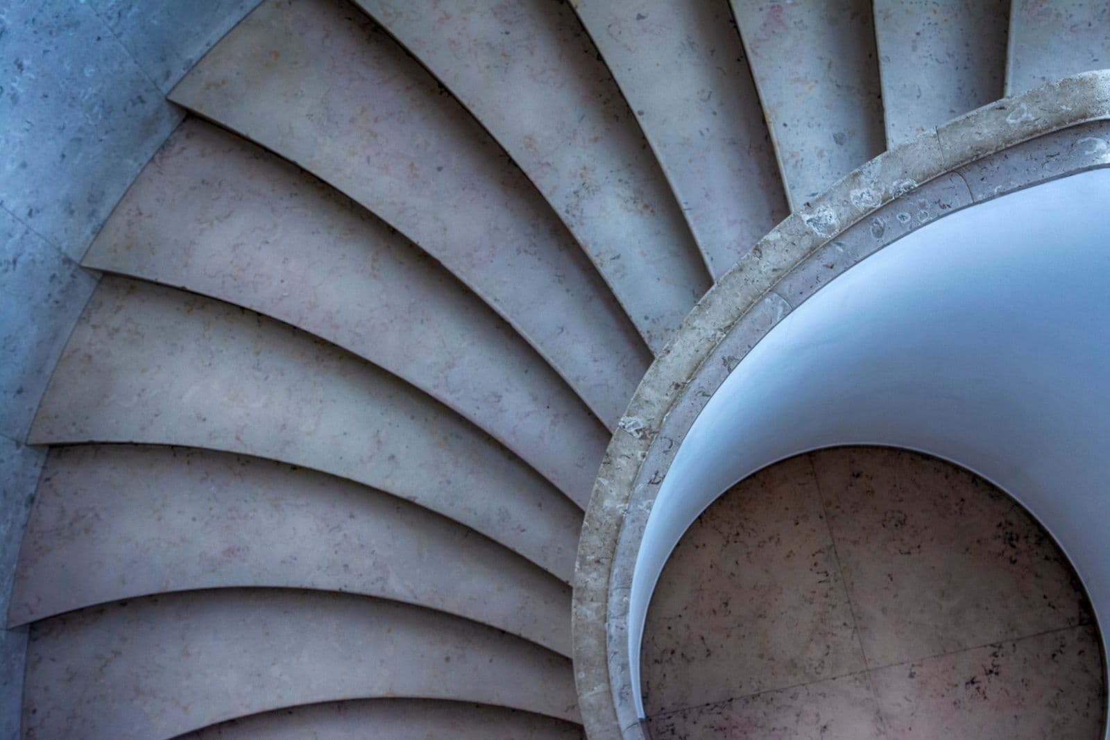 Looking down a curving stone spiral staircase